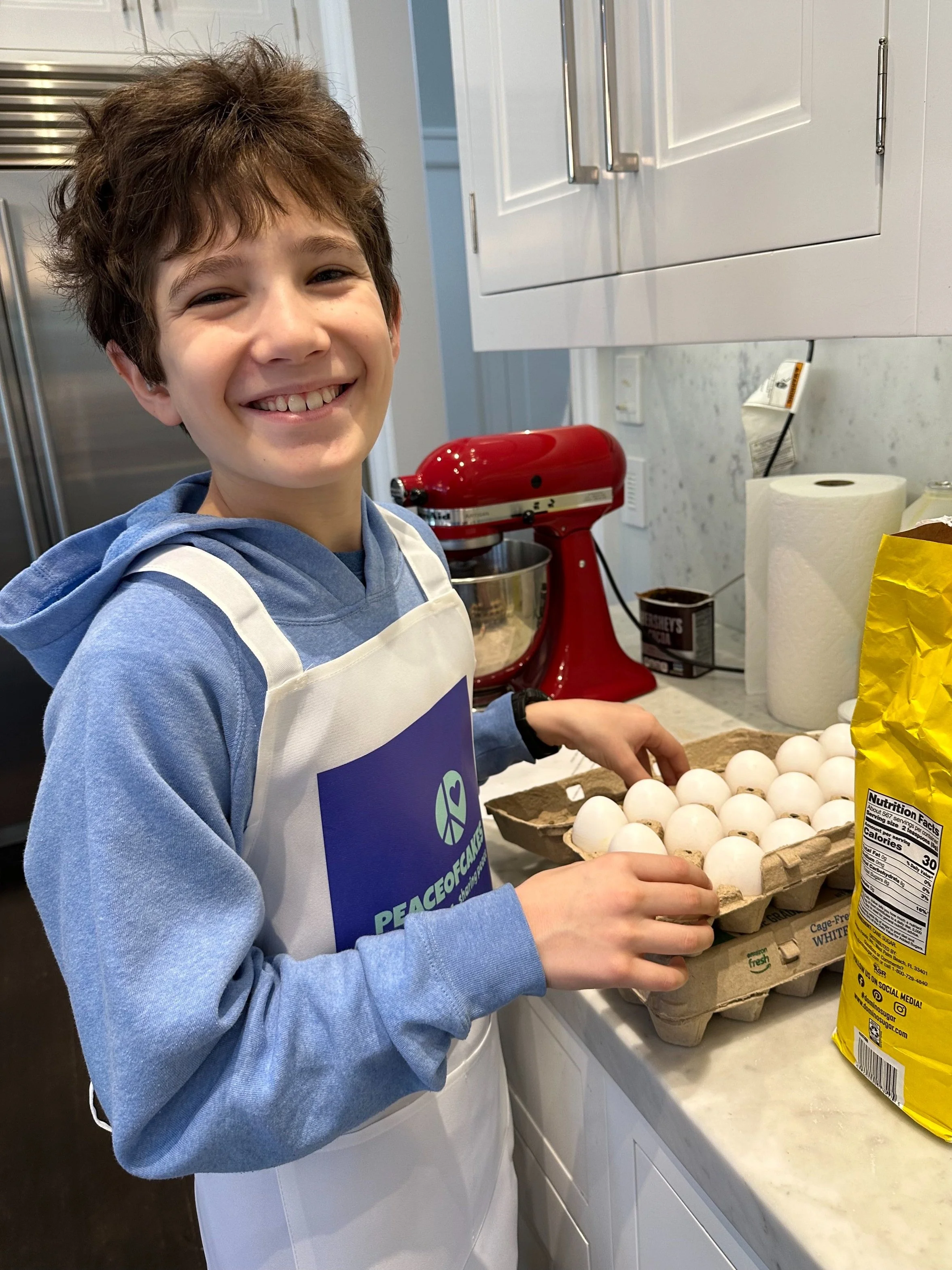 Young PeaceofCakes volunteer beside a display table